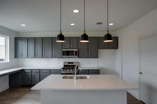 a kitchen with stainless steel appliances a sink a stove a refrigerator and cabinets