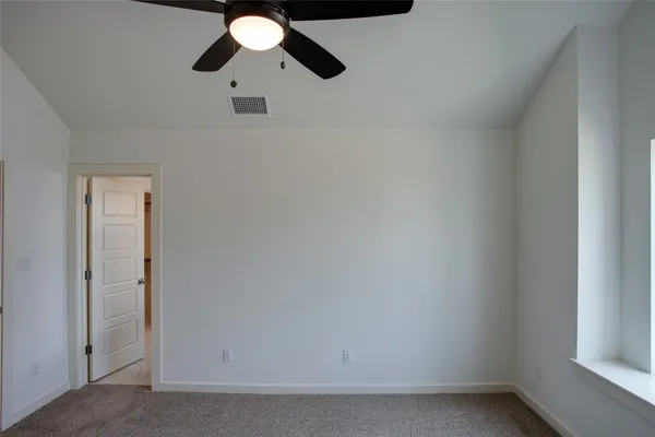 an empty room with closet and a ceiling fan