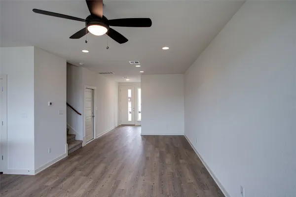 an empty room with wooden floor fan and windows