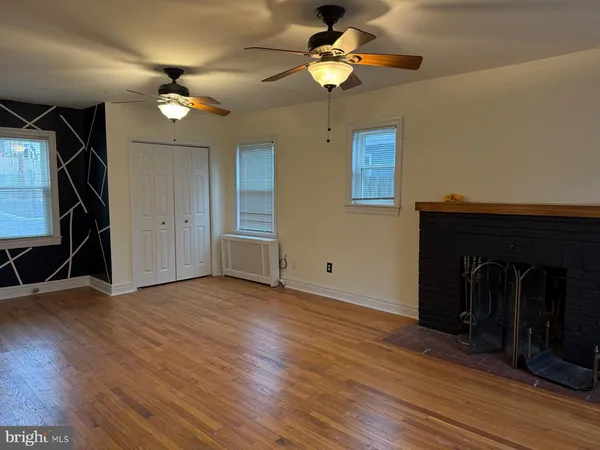 a view of an empty room with wooden floor and a ceiling fan