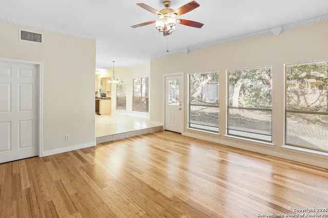 a view of an empty room with a window and wooden floor