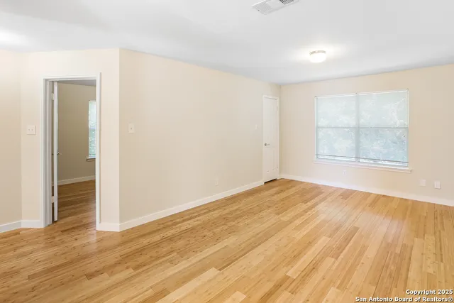 an empty room with wooden floor and windows
