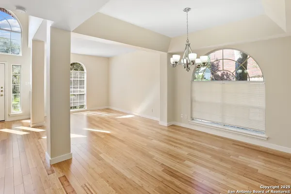 a view of a hallway with wooden floor and chandelier