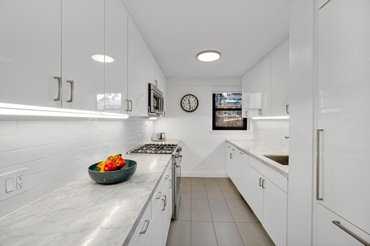 196 East 75th Street, Unit 9A Manhattan, NY 10021 - Photo 4 of 10 a kitchen with granite countertop white cabinets and white appliances