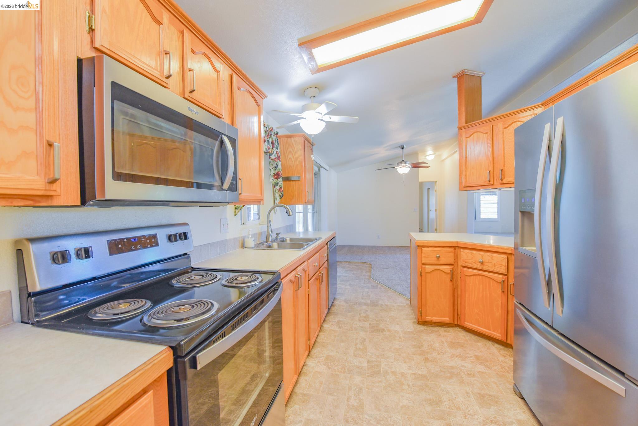 23732 Parrotts Ferry Road, Unit 47 Columbia, CA 95310 - Photo 18 of 21 Kitchen with stainless steel appliances, light countertops, vaulted ceiling, a ceiling fan, and light wood finish cabinets