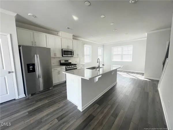 a large kitchen with stainless steel appliances a refrigerator a sink dishwasher a stove and white countertops with wooden floor