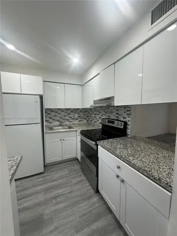 a kitchen with granite countertop white cabinets and white appliances