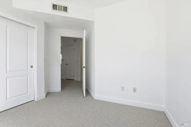 a view of an empty room with closet and a window