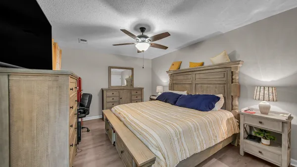 a bedroom with a bed a dresser and a chandelier