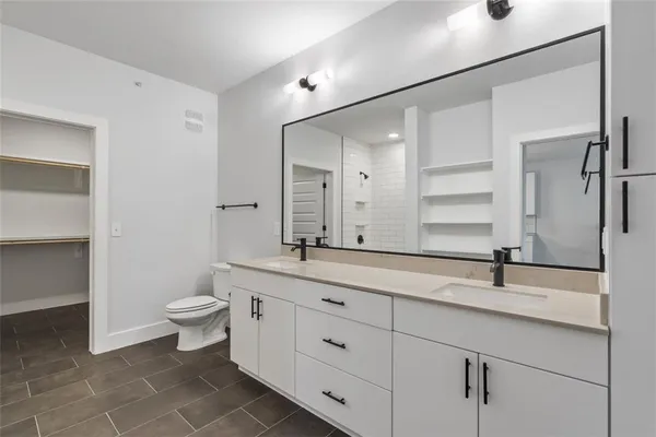 a bathroom with a double vanity sink a toilet and a mirror