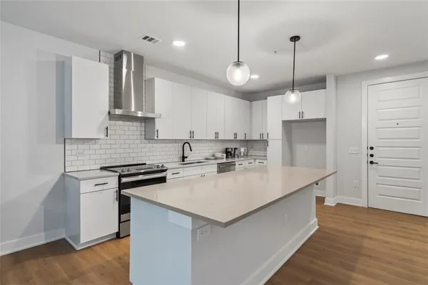 a kitchen with kitchen island a sink a stove a refrigerator and white cabinets
