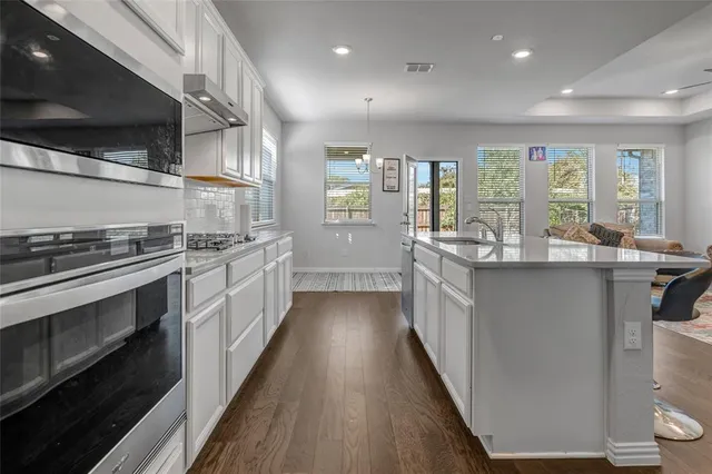 a large kitchen with stainless steel appliances a sink and cabinets
