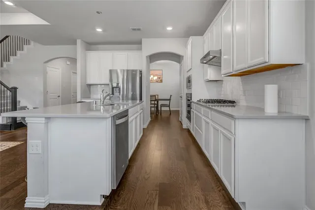 a kitchen with stainless steel appliances granite countertop a lot of counter space and wooden floor
