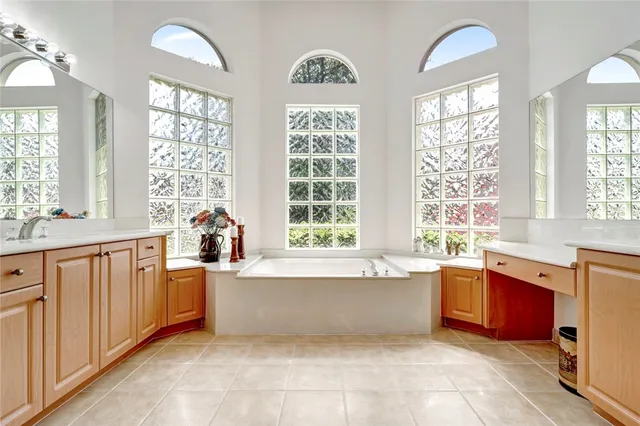a large white kitchen with granite countertop a sink window and cabinets