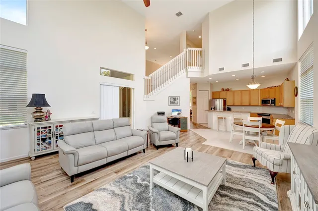 a living room with furniture kitchen view and a wooden floor