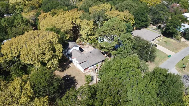 an aerial view of residential house with outdoor space and trees all around