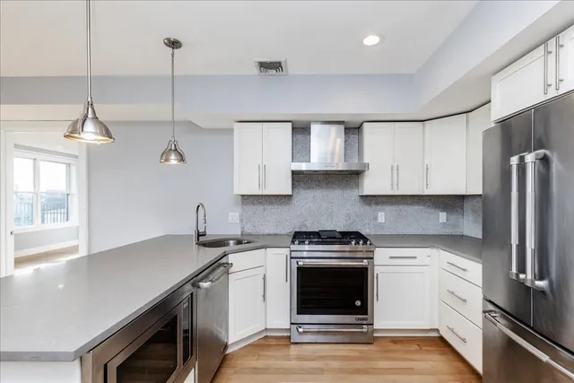 a kitchen with a refrigerator and white cabinets