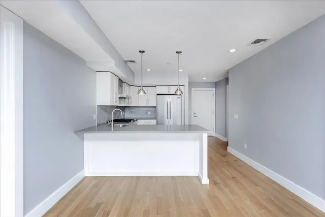 a kitchen with stainless steel appliances a sink stove refrigerator and wooden floor