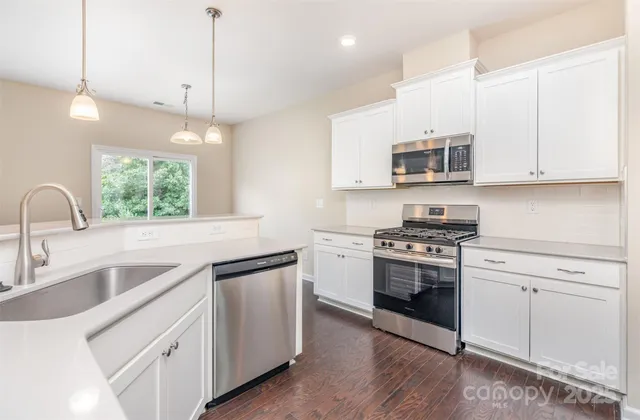 a kitchen with stainless steel appliances granite countertop a sink a stove a microwave and island