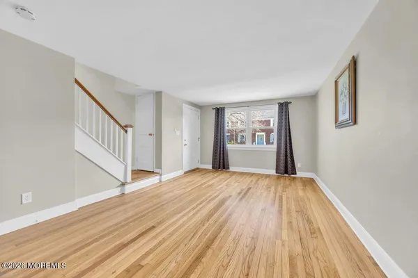 a view of an empty room with window and wooden floor
