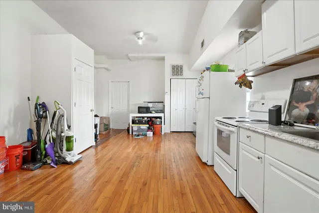 a kitchen with furniture a refrigerator and wooden floor