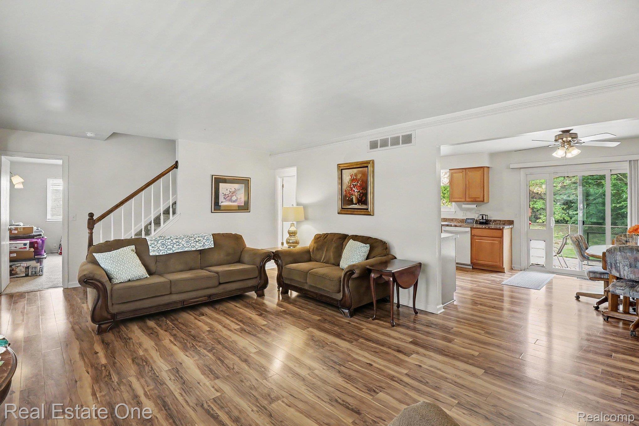 6570 Edgewood Road Canton, MI 48187 - Photo 5 of 22 Living area featuring wood-finish flooring, a white staircase with wood handrails, and a dedicated kitchen space with wood cabinetry and a sliding glass door