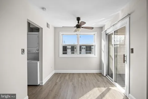 a view of empty room with wooden floor and fan