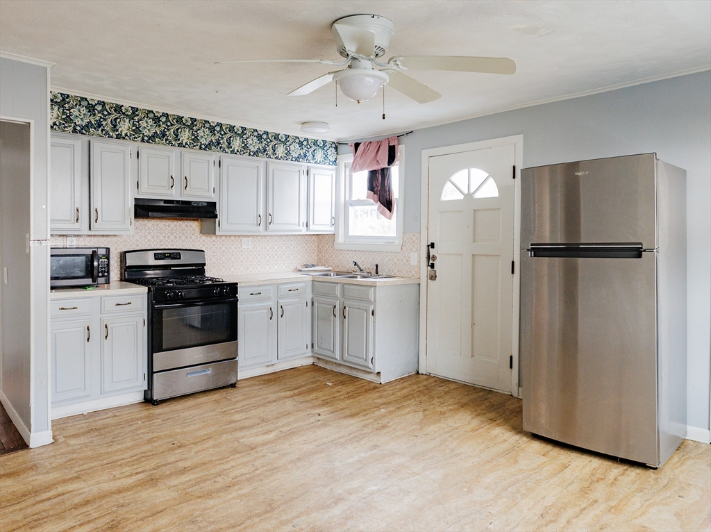 a kitchen with a refrigerator a stove top oven a cabinetry and a chandelier