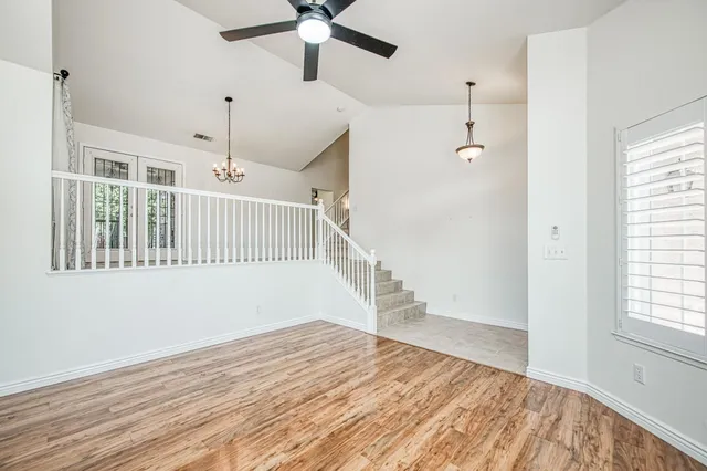 an empty room with wooden floor fan and windows