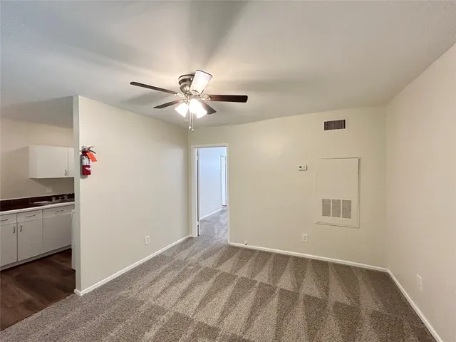 an empty room with windows and ceiling fan
