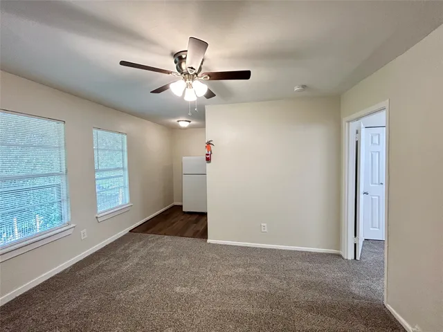 an empty room with windows and fan