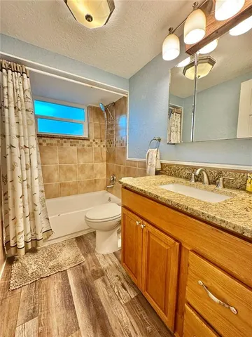 a bathroom with a granite countertop sink a toilet and bathtub