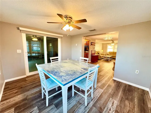 a dining room with wooden floor a chandelier a wooden table and chairs