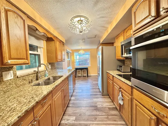 a large kitchen with stainless steel appliances granite countertop a lot of counter space and a sink