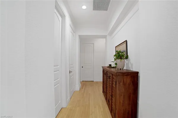a view of a hallway with wooden floor and a chandelier