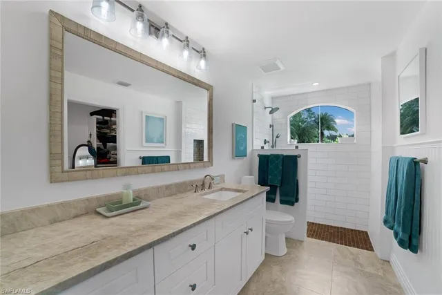 a spacious bathroom with a granite countertop double vanity sink and mirror