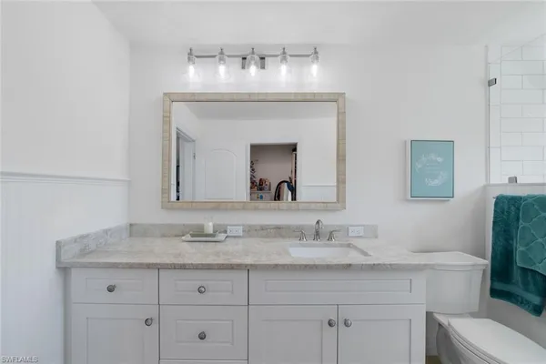 a bathroom with a granite countertop sink a toilet and a mirror