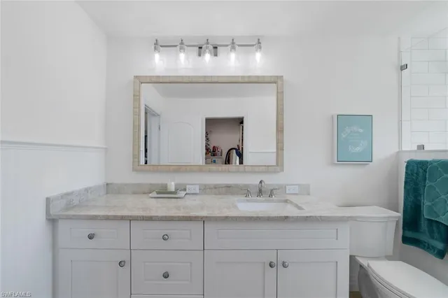 a bathroom with a granite countertop sink a toilet and a mirror