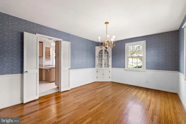 an empty room with wooden floor chandelier and windows
