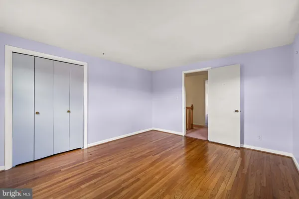 a view of an empty room with wooden floor and closet