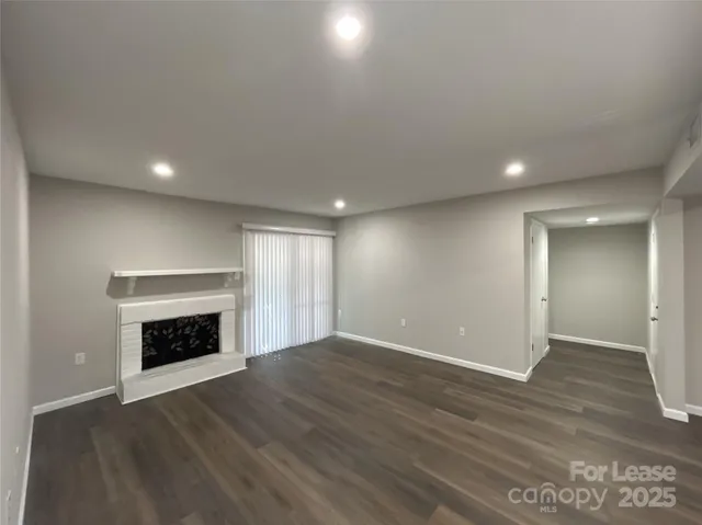 an empty room with wooden floor fireplace and windows