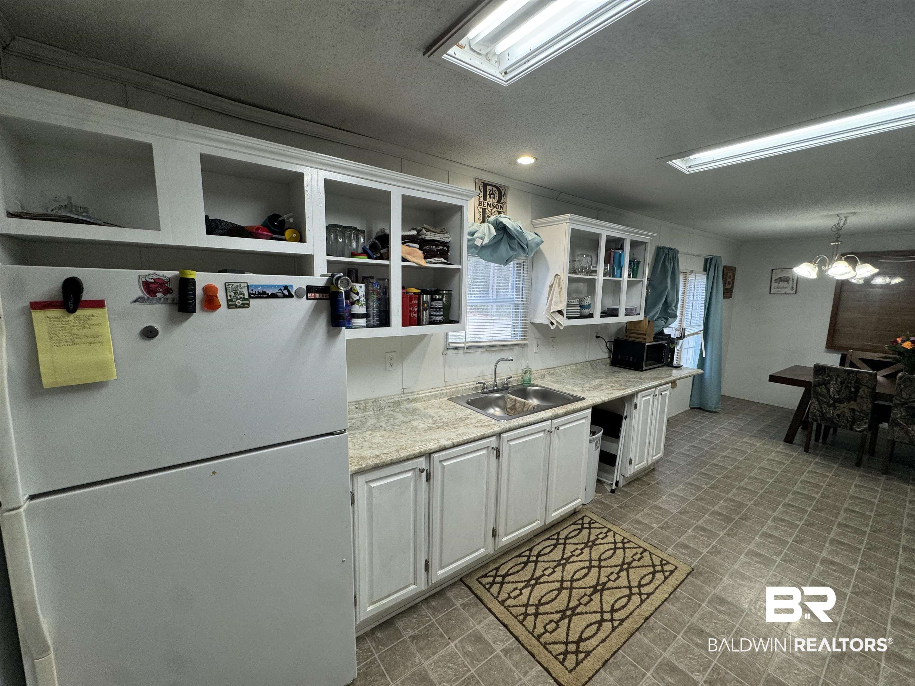 51235 Phillipsville Road Bay Minette, AL 36507 - Photo 34 of 63 Kitchen with freestanding refrigerator, light countertops, white cabinets, open shelves, and a textured ceiling