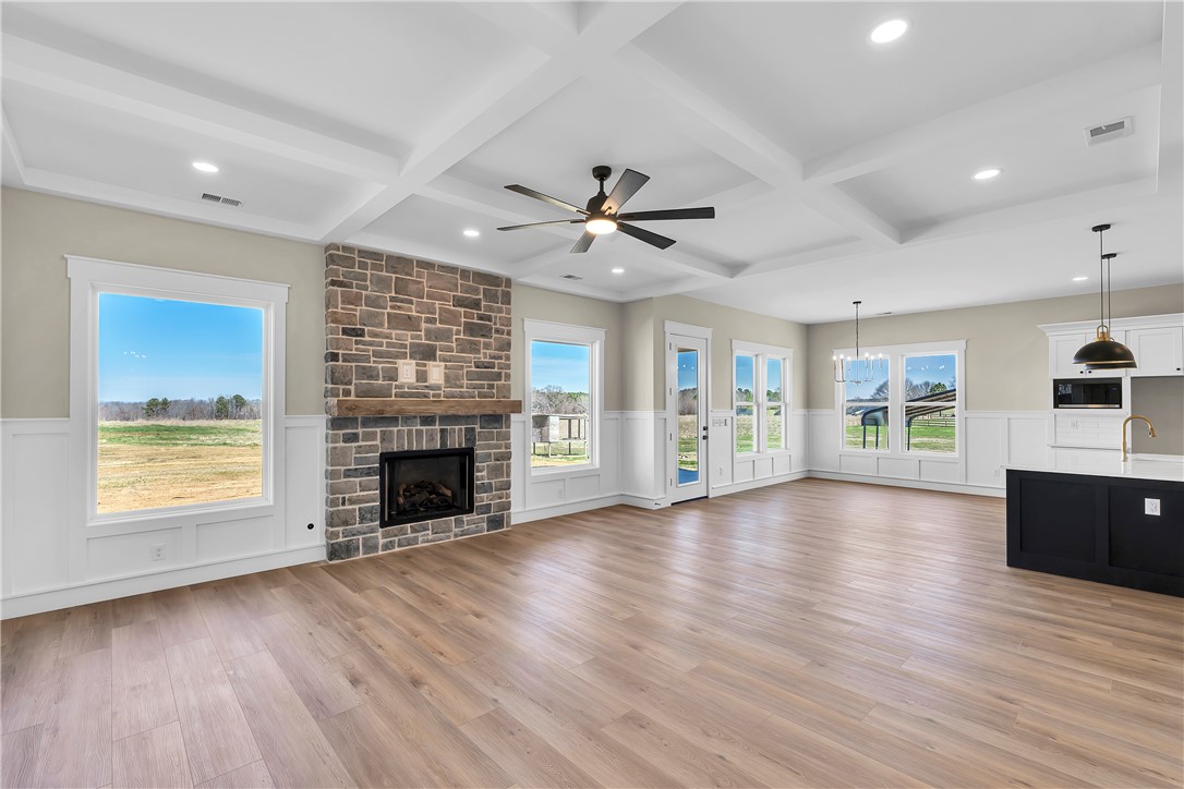 2816 Smith McGee Road Iva, SC 29655 - Photo 17 of 25 A spacious great room boasts a stone fireplace, coffered ceilings, and wide plank flooring, perfect for gatherings.