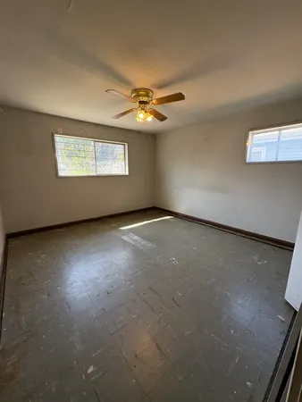 an empty room with windows and fan