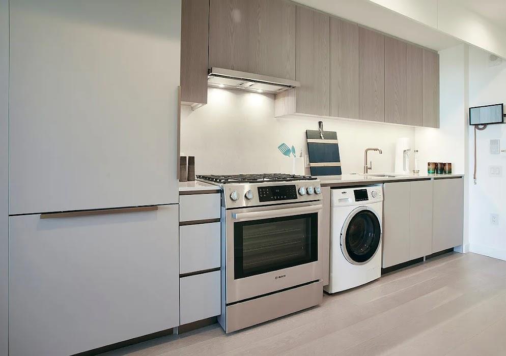 3 Court Square, Unit 2306 Queens, NY 11101 - Photo 4 of 10 Kitchen featuring stainless steel range with gas cooktop, freestanding refrigerator, washer / dryer, modern cabinets, and light countertops