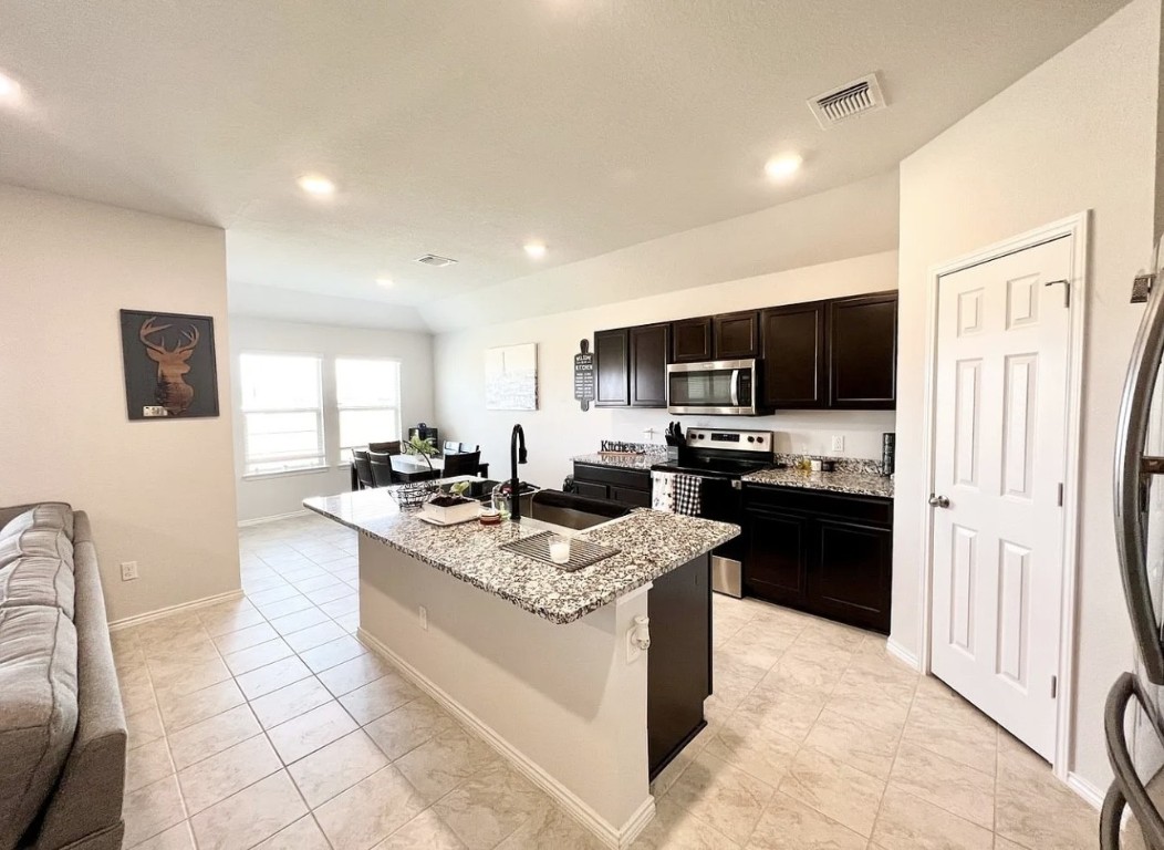 544 Taggart Trail Jarrell, TX 76537 - Photo 17 of 19 a large kitchen with stainless steel appliances granite countertop a stove top oven a sink a stove a dining table and chairs