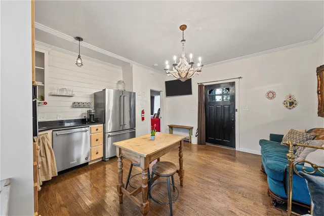 a open kitchen with stainless steel appliances granite countertop a refrigerator a stove a sink dishwasher and a dining table with wooden floor