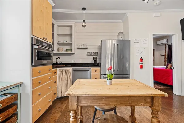 a kitchen with stainless steel appliances kitchen island granite countertop a refrigerator a stove top oven and a dining table with wooden floor