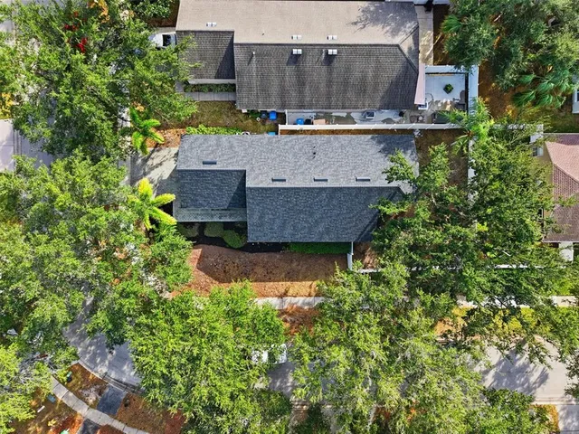 an aerial view of a house with a yard and a large tree