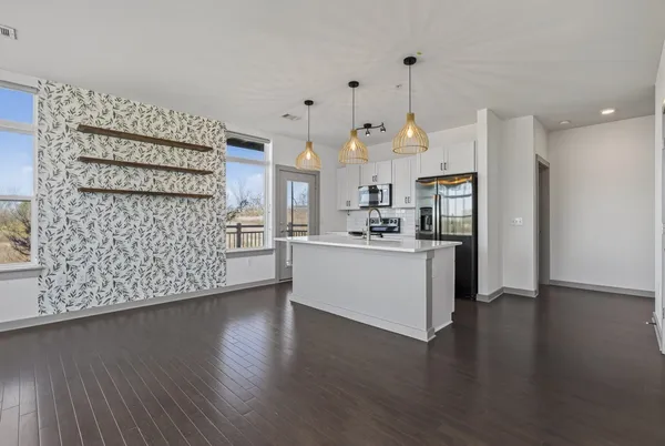 a view of a kitchen with stainless steel appliances granite countertop a refrigerator a sink a stove and a wooden floors